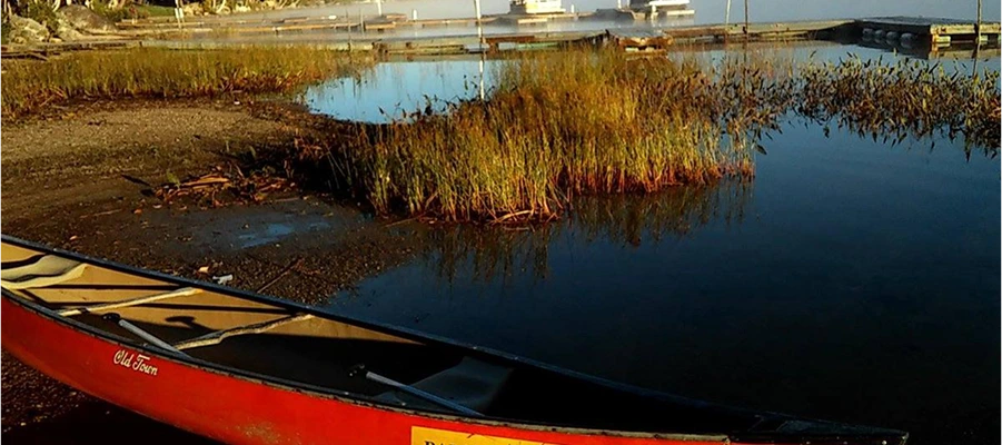 Red canoe by a tranquil lakeside.