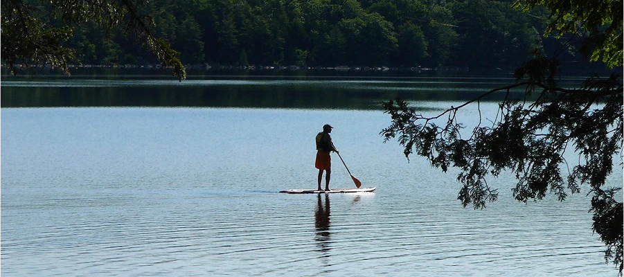 Person paddleboarding on a calm lake.
