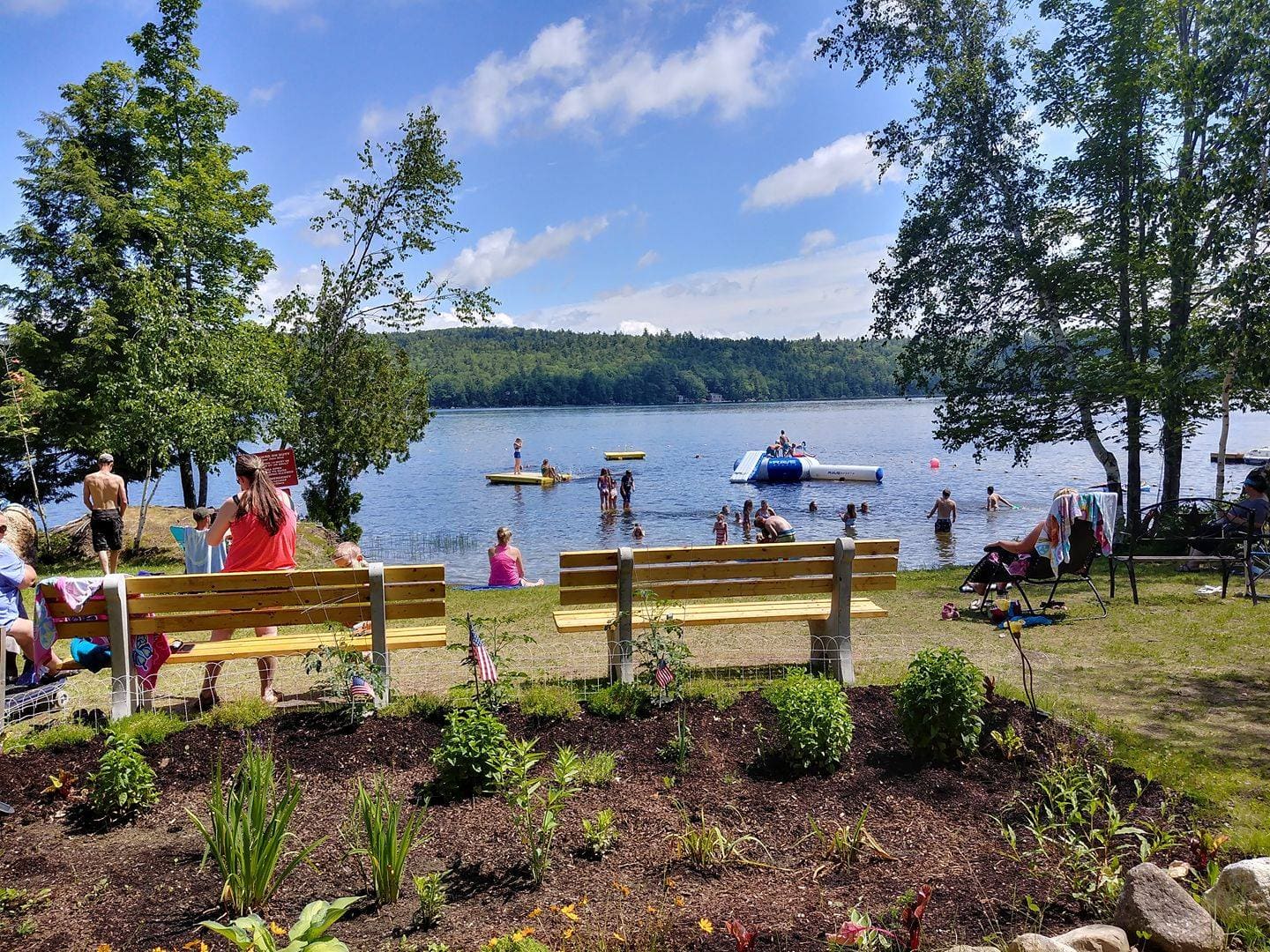 A group of people sitting on top of benches near the water.
