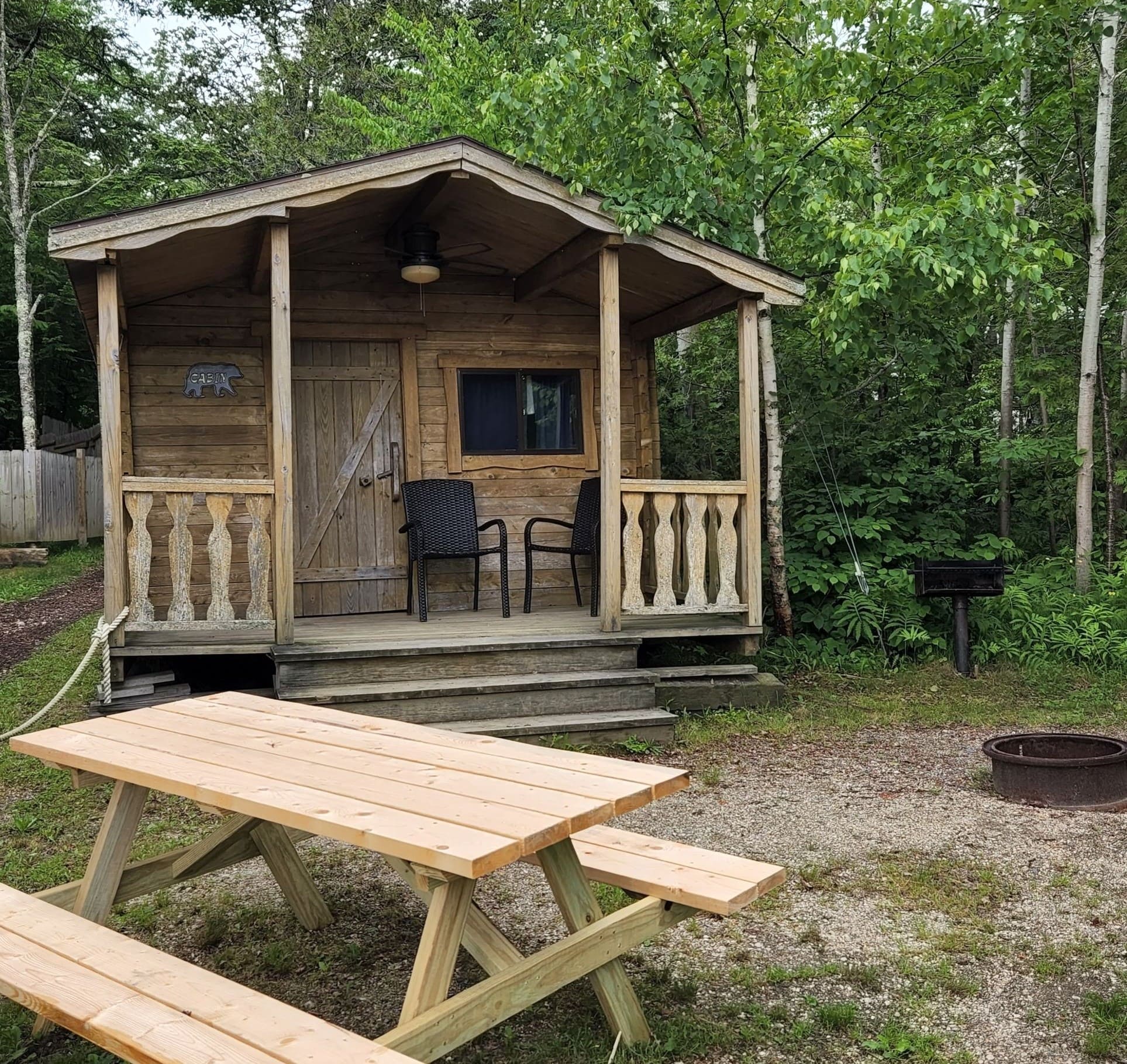 A wooden cabin with picnic table and chairs.