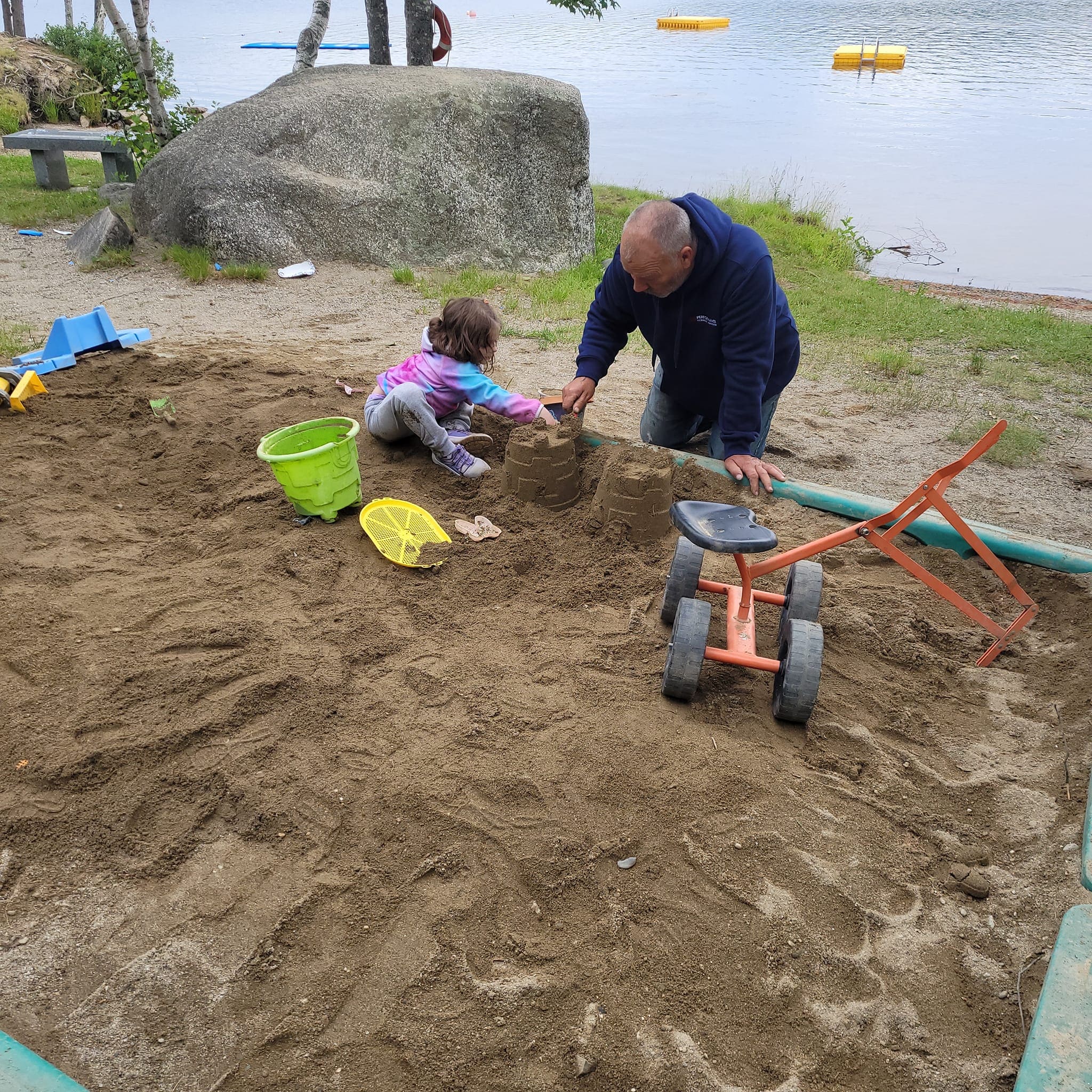 A man and child playing in the sand.